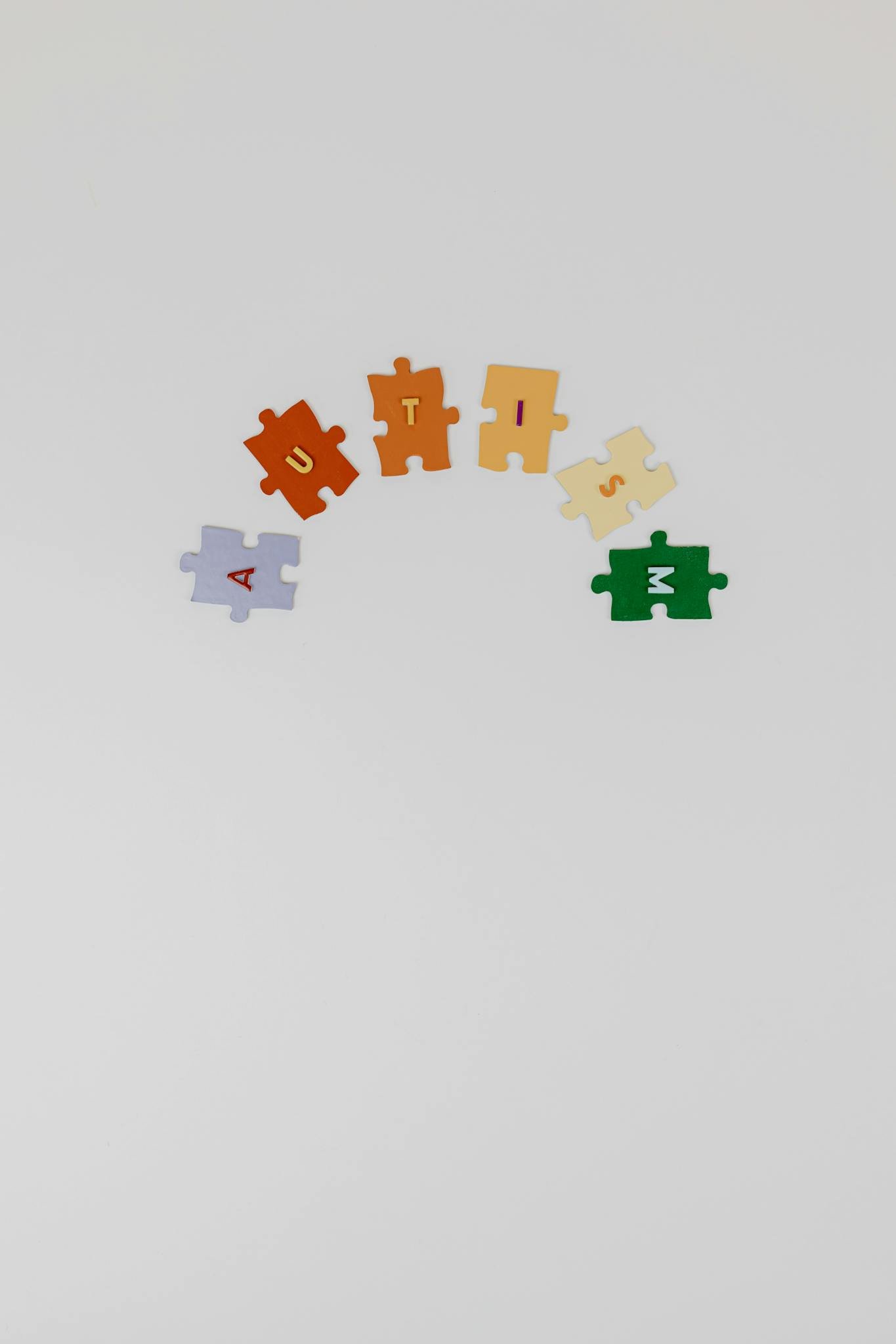 Colorful puzzle pieces spelling 'autism' on a white background symbolizing autism awareness.